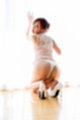 Kneeling against window looking over her shoulder wearing lingerie white high heels
