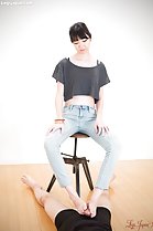Looking down seated on stool wearing jeabs hard cock between her bare feet