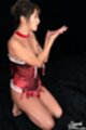On her knees wearing red basque cum covered hands raised