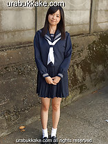 Kogal standing outdoors beside wall long hair over her shoulders hands clasped together